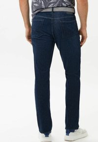 Mörkblå raka jeans för män, tillverkade av denimtyg. Har två bakfickor och ett midjeband med ett grått bälte.