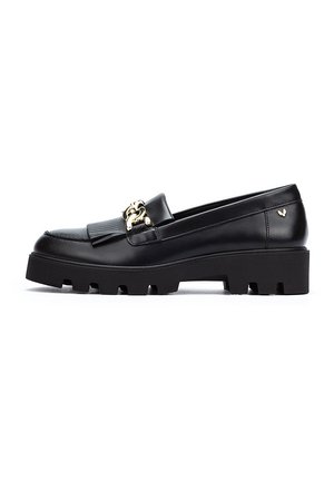 Mocasines de cuero negro con una suela gruesa y texturizada, que presentan un acento de hardware dorado y un detalle de diseño plisado en la parte superior.