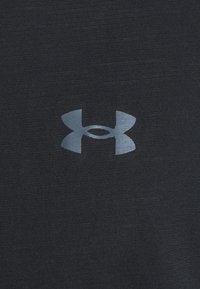 Svart atletisk tyg som visar en slät textur, med en reflekterande grå Under Armour-logotyp centrerad på bröstet.