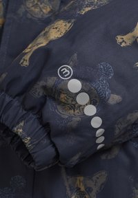 Marinblått tyg med ett fiskbensmönster som har guld- och blå hundtryck. Elastisk muddkant, cirkulära grafiska detaljer och tygstrukturen synlig.