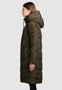 Olive green puffer coat with a hood, featuring quilted detailing, zippered side pockets, and a relaxed fit. Soft, smooth texture.