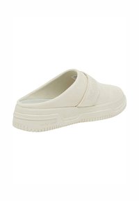 Slip-on fottøy med mykt, beige overmateriale, som har et teksturert bånd på midten og en mønstrete gummisåle.