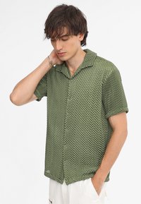 Groene korte mouwen shirt met een gestructureerd honingraatpatroon, knoopsluiting aan de voorkant en een ronde kraag. Lichtgewicht materiaal.