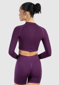 Lilla langærmet crop top og højtaljede shorts lavet af glat, strækbart stof med ribbet tekstur og sømløst design.