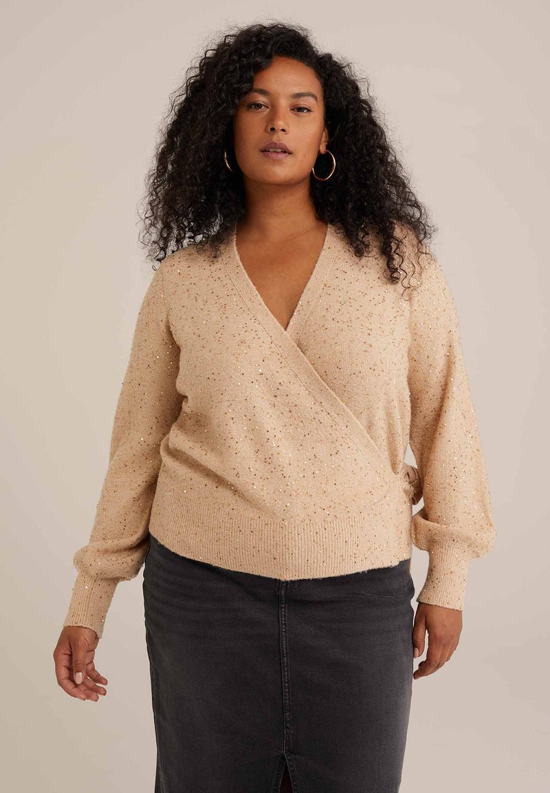 Bežna ovita jopica z V-izrezom, dolgimi rokavi in teksturiranim zaključkom z zlatimi pikami. Kombinirana s temno sivo denimsko krilom.