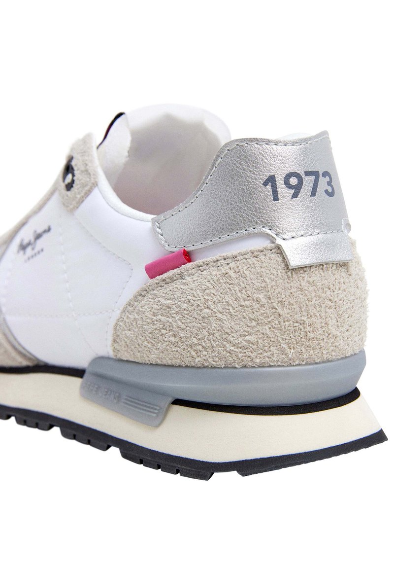 Sneaker con tomaia in pelle bianca, dettagli in suede beige, linguetta in metallo argentato con "1973", dettagli rosa e neri e suola in gomma texture.