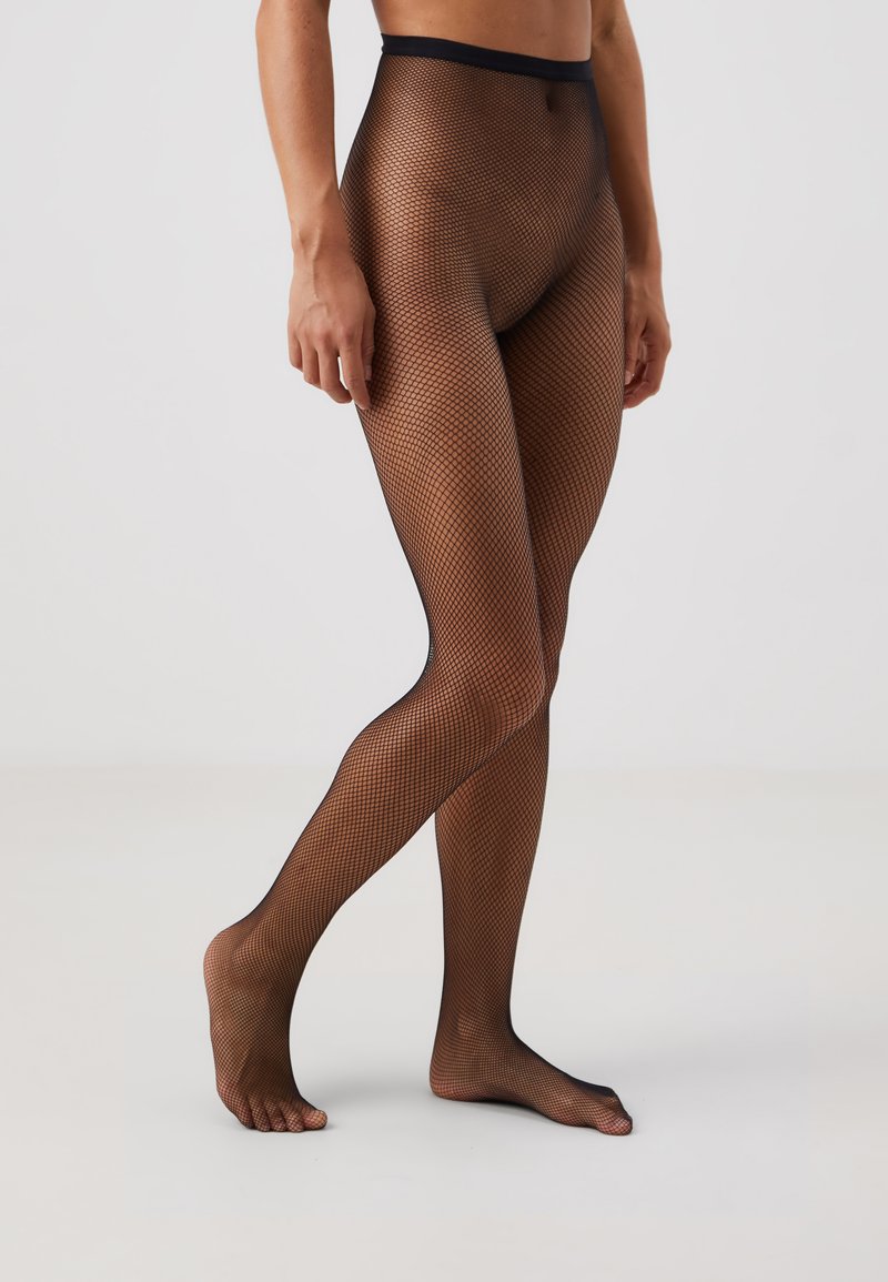 Collant in rete nera con un motivo a maglia stretto, vita elasticizzata e texture trasparente. La zona dei piedi è aperta, consentendo di mostrare i piedi nudi.