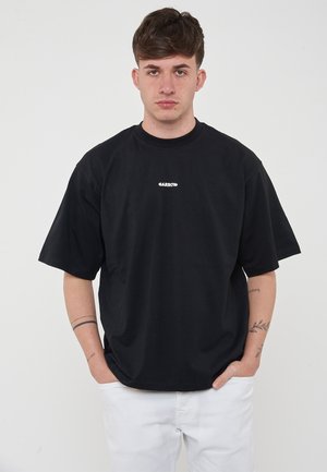 T-shirt nera in cotone con maniche corte, vestibilità rilassata. Presenta un piccolo logo bianco centrato sul petto. Design semplice senza fantasie.
