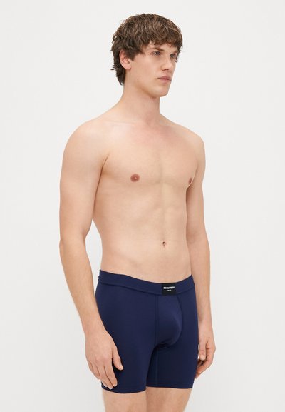 Μαύρο μπλε μποξεράκι με λεία υφή και ελαστική ζώνη που διαθέτει ετικέτα λογότυπου; Η εφαρμοστή σχεδίαση αναδεικνύει το σχήμα με μια προσαρμοσμένη θήκη.