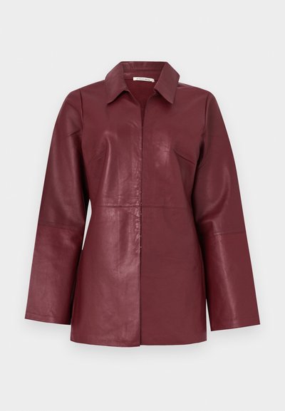 Giacca in pelle bordeaux a maniche lunghe con colletto e cerniera frontale, vestibilità aderente e texture liscia.