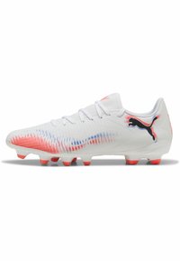 Des chaussures de football blanches avec une surface texturée, des accents en dégradé rouge et bleu, six crampons orange et un logo noir sur le côté.