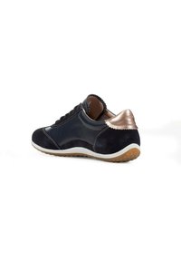 Zapatillas de ante azul marino con un panel de cuero suave, forma redondeada, Media suela blanca y un acento en el talón de bronce metálico. Suela de goma.