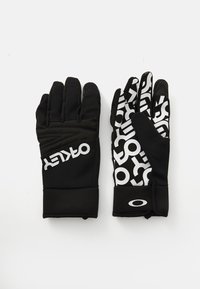 Une paire de gants Oakley noirs, le gant gauche uni avec le logo, le gant droit à motif avec le texte et le logo Oakley blancs sur la sangle du poignet.
