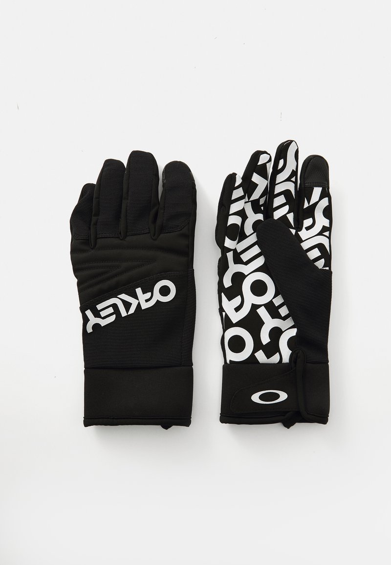 Une paire de gants Oakley noirs, le gant gauche uni avec le logo, le gant droit à motif avec le texte et le logo Oakley blancs sur la sangle du poignet.