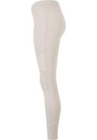 Leggings beige avec une texture lisse, une coupe ajustée et des détails sur les coutures latérales. Équipés d'une large ceinture douce pour plus de confort.