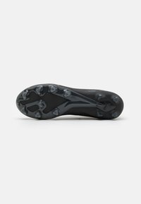 Sole di scarpini da calcio neri con tacchetti sagomati, progettata per garantire aderenza; texture liscia con motivi sottili e una forma aerodinamica elegante.