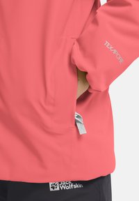Wasserfeste Koralljacke mit TEXAPORE-Technologie. Verfügt über eine Seitentasche und ein reflektierendes Logodetail am Ärmel. Schwarzes Branding am Saum.