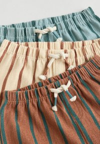 Three pairs of drawstring shorts: light blue with teal stripes, cream with brown stripes, and brown with teal stripes. Texture is soft.