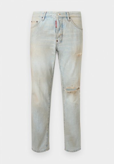 Jean en denim clair avec déchirures usées sur la cuisse droite et le genou, conception à cinq poches, et étiquette de marque rouge sur la zone de la fermeture éclair avant.