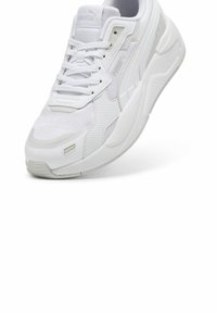 Baskets blanches de sport en mesh et matériaux synthétiques, avec bout rond, fermeture à lacets à l'avant, et accents texturés sur les côtés et la semelle.