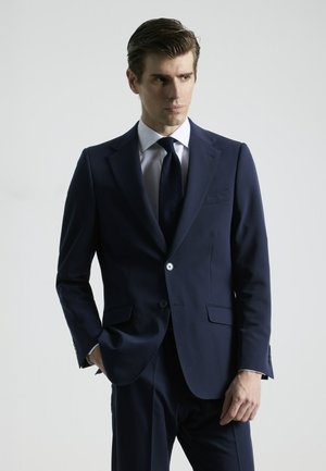 Chaqueta de traje azul marino hecha de tela suave, con cierre de un solo botón, solapas de muesca y dos bolsillos frontales. Corte ajustado.