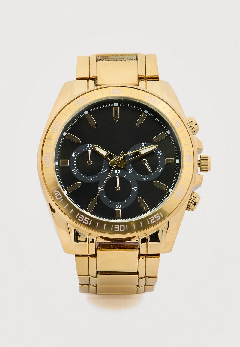 Chronograafhorloge van metaal met goudkleurige afwerking, zwarte wijzerplaat, drie subdials en opvallende uurmarkeringen. Heeft een ontwerp met een schakelband.