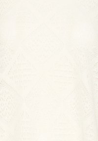 Krēmveida adīts audums ar simetrisku dimanta un zigzaga rakstu, kurā ir mazi atvērtie caurumi un teksturētas dūrienas.