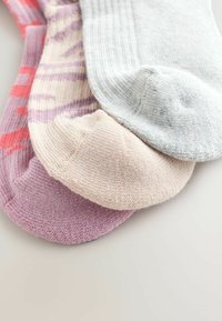 Tri para nogavic: ene rožnate s vzorcem, ene svetlo sive in ene bledo rožnate. Vse imajo mehko, rebrasto teksturo.