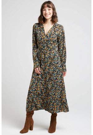 Robe portefeuille florale en tissu sombre avec de longues manches, présentant des motifs jaunes et bleus, un décolleté en V et une silhouette fluide.