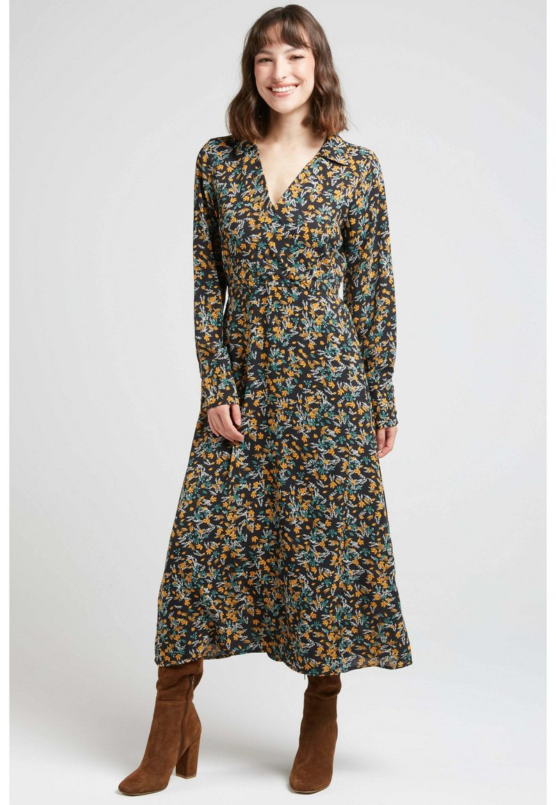 Robe portefeuille florale en tissu sombre avec de longues manches, présentant des motifs jaunes et bleus, un décolleté en V et une silhouette fluide.