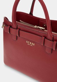 Rode gestructureerde tas van faux leer met twee korte handvatten, gouden rits en merkdetail. Beschikt over een strakke uitstraling en elegante accenten.