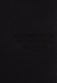 Črn material z gladko teksturo, ki vsebuje embosirano besedilo: "OD GORA DO MESTNIH ULIC PO BLUE RIDGE."