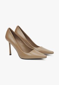 Nude szpilki z szpiczastym noskiem, górą z gładkiej skóry, wysokim obcasem stiletto i minimalistycznym designem. Czarna podsuwka akcentująca.