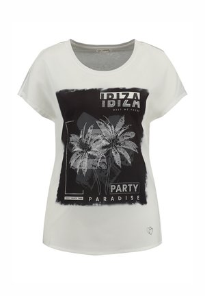 La camiseta blanca presenta un diseño gráfico negro con palmeras, el texto "IBIZA PARTY PARADISE" y un adorno en forma de corazón en el dobladillo.