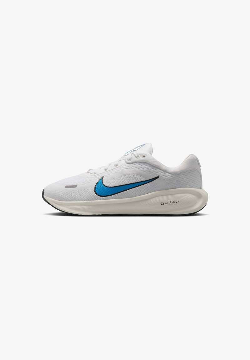 Biele športové topánky s modrým Swooshom Nike, textúrovaný sieťovaný zvršok, mäkká pena v strednej podrážke a čierna gumová podrážka. Obsahujú šnúrky a značenie.