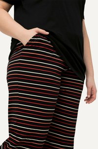 Pantaloni a strisce nere con linee orizzontali rosse, bianche e rosa, dalla vestibilità comoda e con tasche laterali.