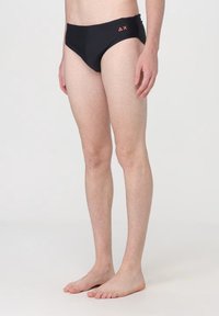 Culotte da nuoto nere con design a vita bassa, dotate di un dettaglio con logo arancione sulla cintura. Realizzate in tessuto liscio e elastico.