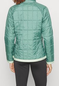 Světle zelená prošívaná bunda s hladkým povrchem, se stojáčkem, raglánovými rukávy a kontrastním světle zeleným lemem.