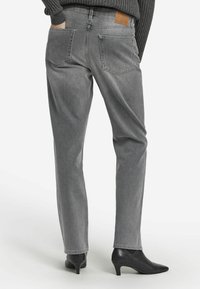 Grå denimjeans med raka ben, bakfickor och en brun läderlapp vid midjan. Matchade med svarta stövlar med klack.