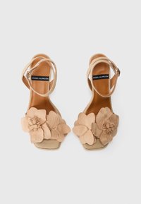 Nude hakken sandalen met een brede band versierd met drie stoffen bloemen. Gladde leren inlegzool, verstelbare enkelband en open tenen.