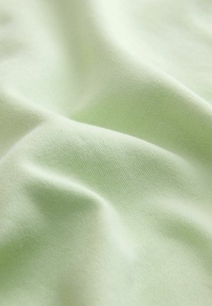 Material moale, verde pal, cu o textură fină de tricotaj vizibilă și falduri delicate care creează unde line și fluide pe suprafață.