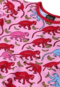 Pulower z różowego materiału zdobionego czerwonymi i niebieskimi wzorami małp trzymających banany, uzupełniony czerwonym dekoltem.