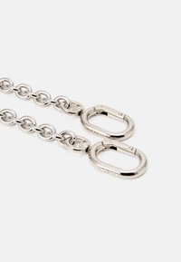 Catena in metallo argento con anelli ovali e due grandi moschettoni curvi a ciascun estremo. Texture liscia e superficie lucida.