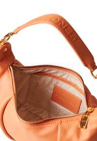 Leather shoulder bag in soft coral, featuring a zip closure, metallic hardware, textured lining, and an inner pocket with brand label.