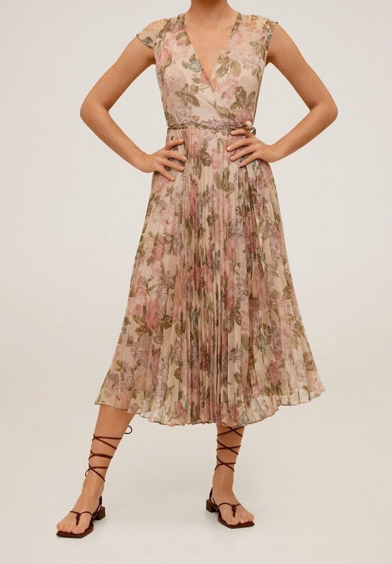 Gefaltetes Blumenkleid mit V-Ausschnitt, kurzen Ärmeln und tailliertem Schnitt, in Rosa-, Grün- und Beigetönen; kombiniert mit Riemchensandalen.