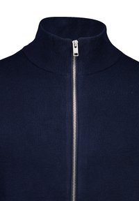 Tummansininen neulottu vetoketjullinen neulepaita, jossa on korkea kaulus ja hopea vetoketju. Paidassa on ribbineulepinta ja saumaamaton muotoilu.