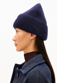 Marineblau, gestrickte Mütze mit konischer Form. Hergestellt aus plüschigem Material, mit einem strukturierten Muster und einem umgeschlagenen Saum.