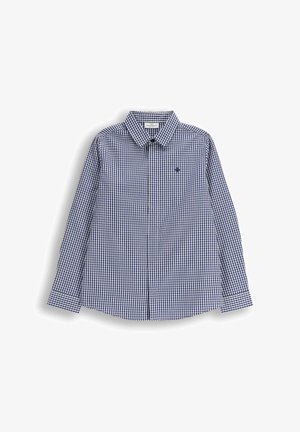 Niebiesko-biała koszula w kratę z długim rękawem i kołnierzykiem na guziki, z małym logo na piersi oraz zaokrąglonym dołem.