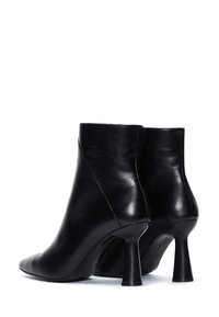 Bottes chevilles en cuir noir avec un bout pointu et un talon sculpté, présentant une texture lisse et une silhouette élégante.