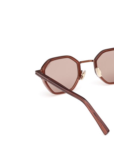 Ochelari de soare octogonali cu un cadru din plastic translucent maroniu, lentile colorate în maro și accente aurii pe balamale. Brațe subțiri și drepte.